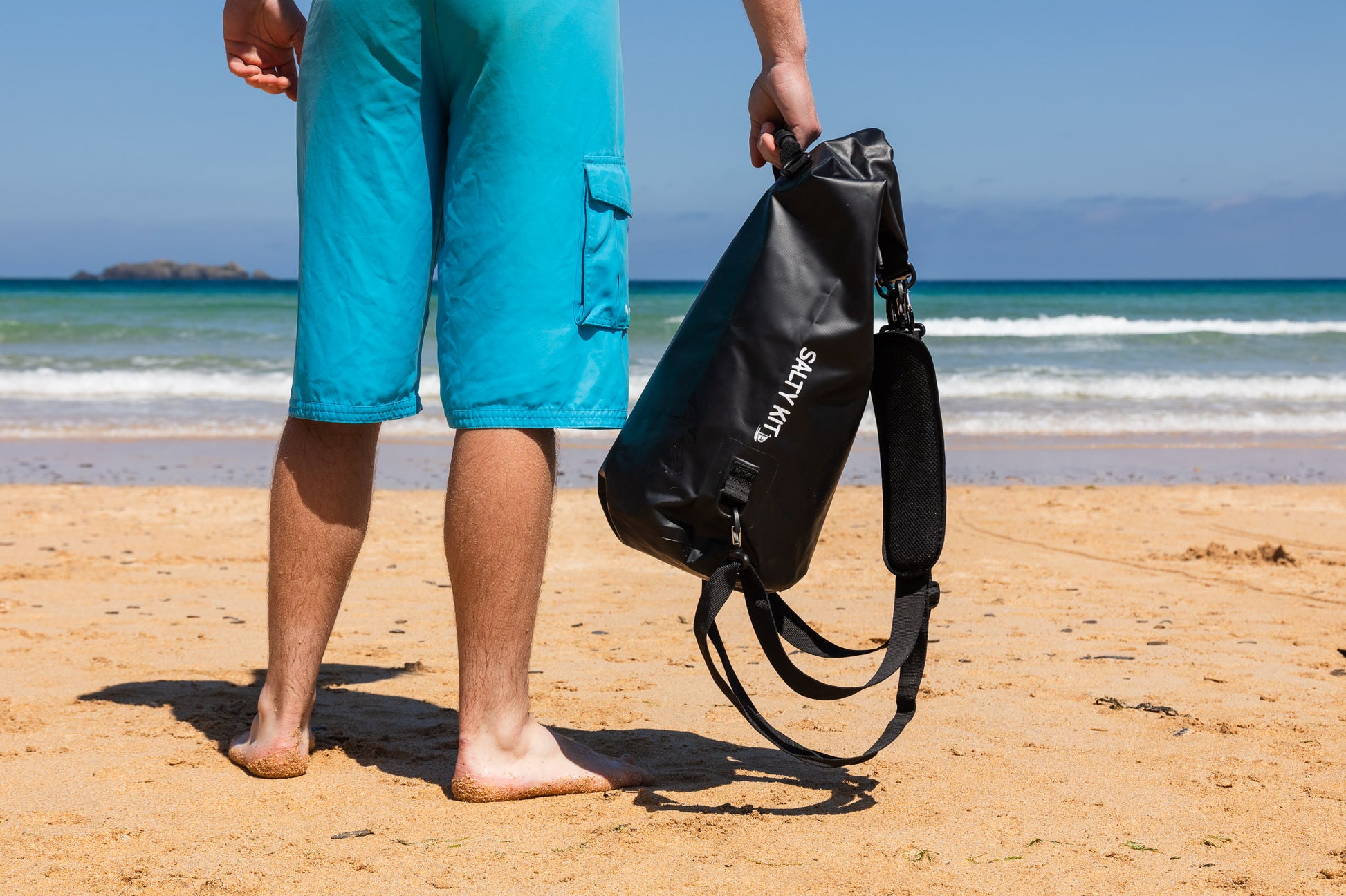 best cool dry bag in black 20 litres, a man is holding one standing on the beach