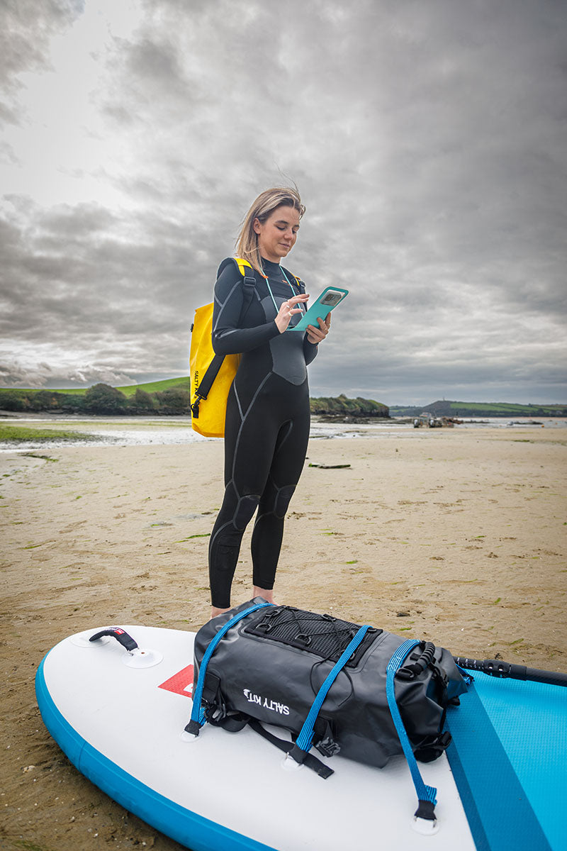 girl taking photo using green phone pouch wearing 20L dry bag in yellow by salty kit