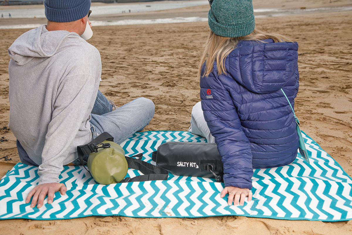 couple on rock beach with salty kit 5 litre bags