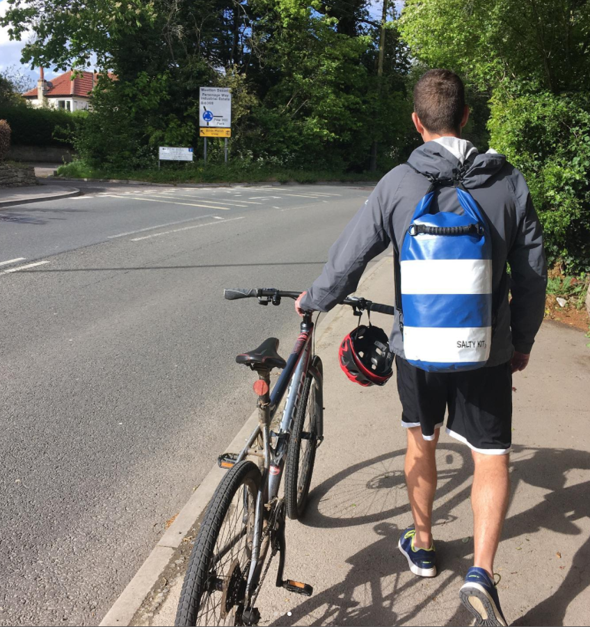 a boy cyclist walking with his bike wearing the nautical look salty kit dry bag