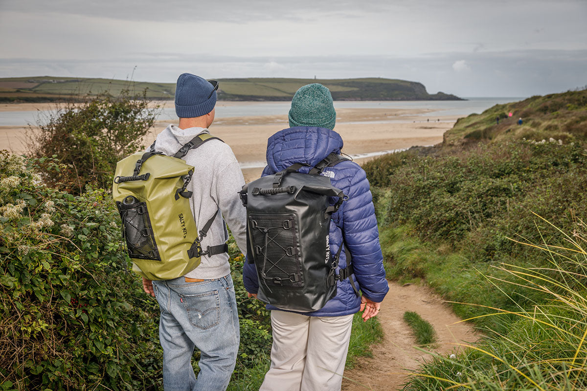 a couple hiking through the sand dunes towards brea hill wearing winter clothes and the olive and black 30 litre salty kit bag