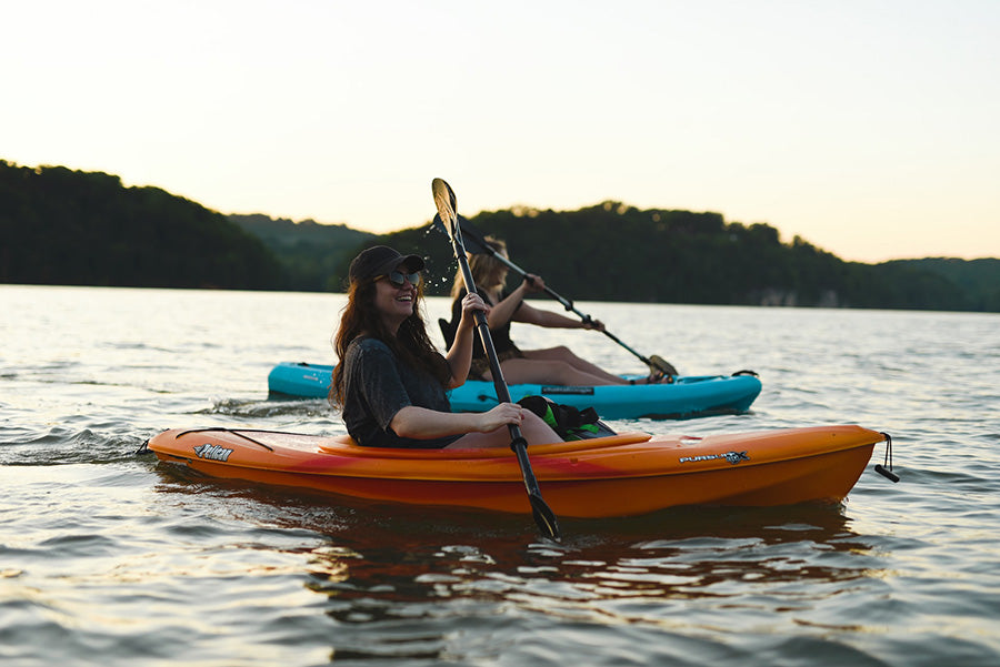 2 girls kayaking and laughing in calm waters