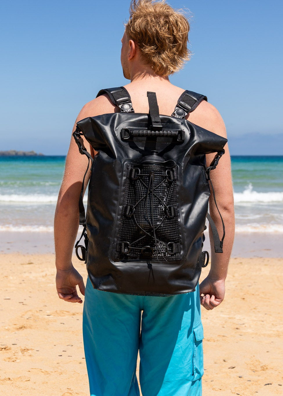 the smart black 30 litre salty kit backpack with detachable comfort straps styled by man on a Cornish beach