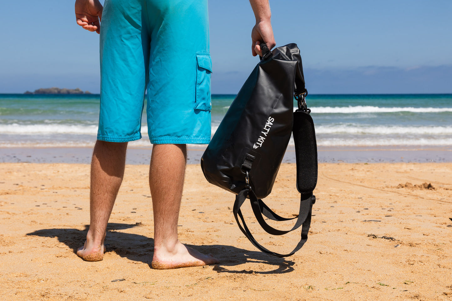 best cool dry bag in black 20 litres, a man is holding one standing on the beach