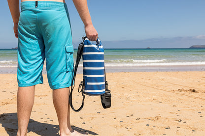 best small dry bag being held by a man on a Cornish beach in a blue and white stripe design 