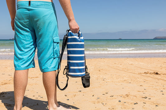 man holding the 5 litre salty kit blue and white stripe nautical look dry bag on harlyn beach cornwall 