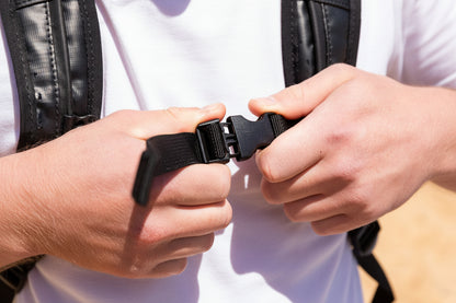Person adjusting a black strap on a leather jacket.