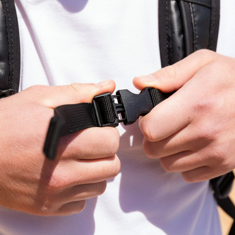 Person adjusting a black strap on a leather jacket.