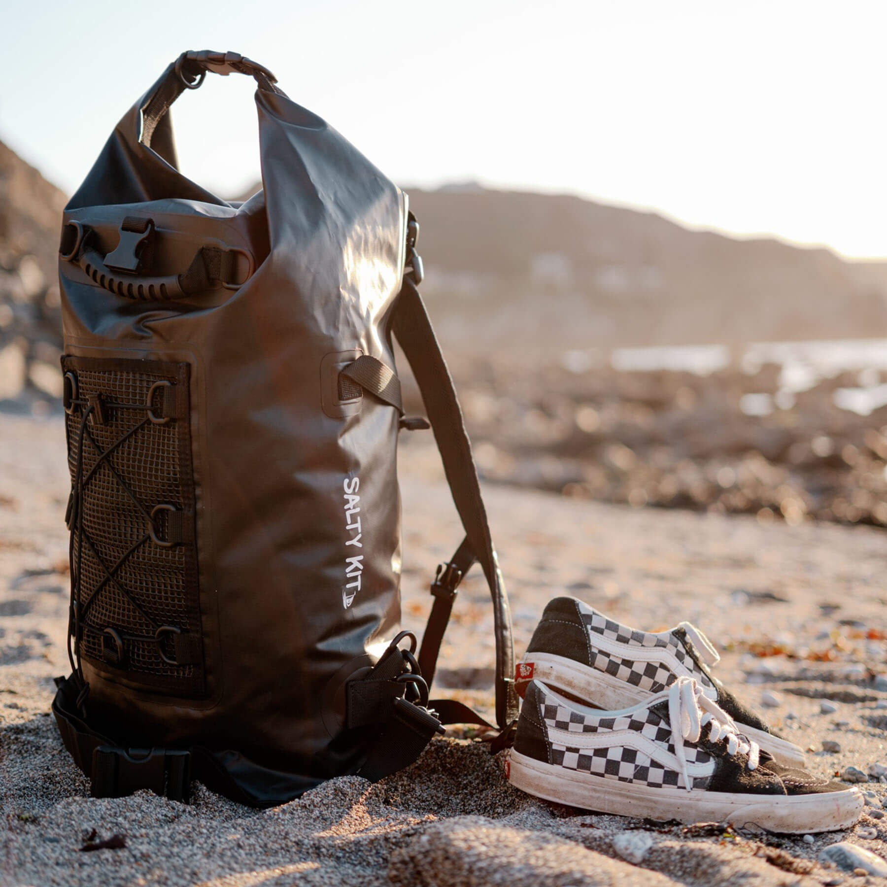 black 30 litre waterproof backpack by salty kit on the beach with trainers 
