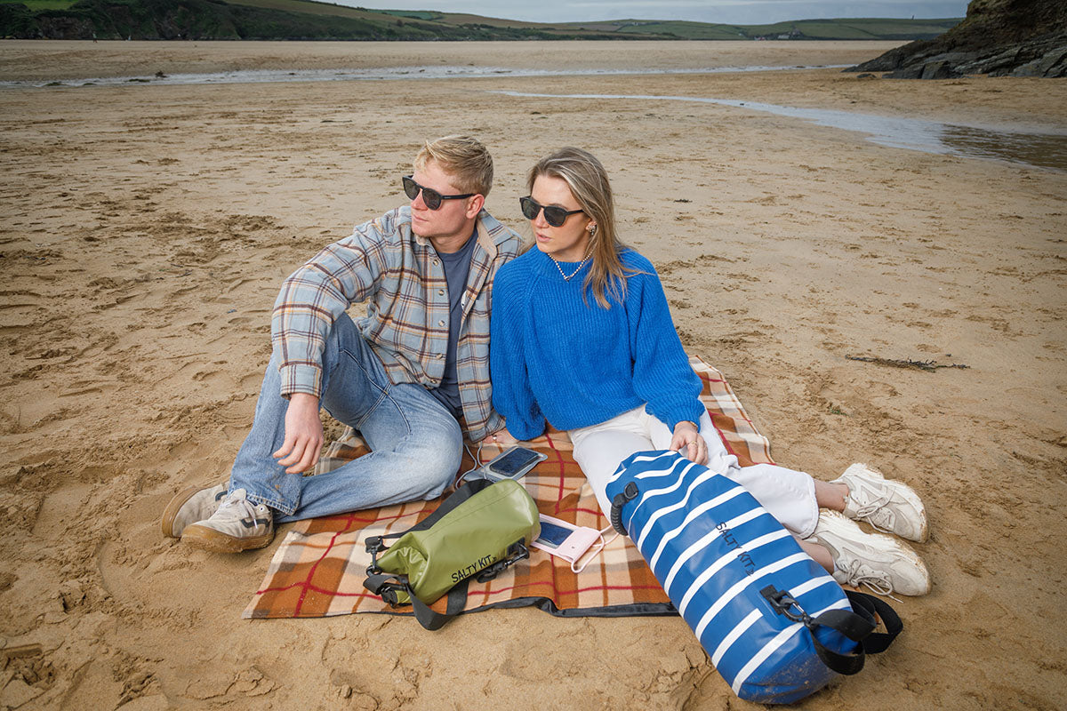 couple on beach with salty kit dry bags and phone cases