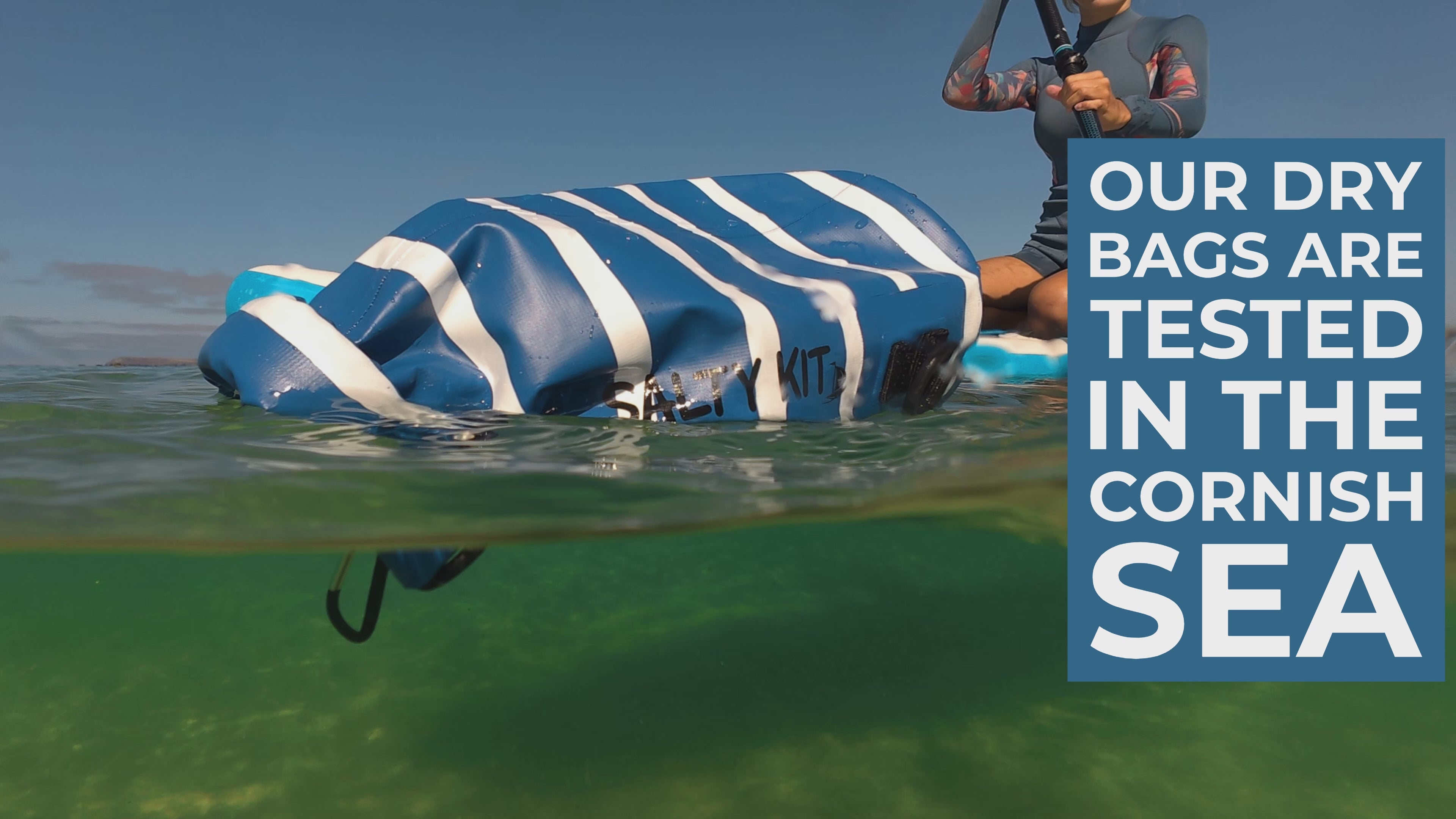 Load video: the salty kit nautical 5 litre bag floating in the sea with a paddleboarder with the wording "our dry bags are tested in the cornish sea"