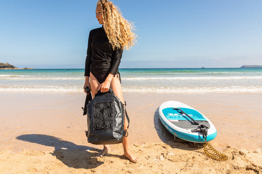 paddleboard bag nice and large with 30 litre capacity black and a backpack being styled by a lady on a Cornish Beach